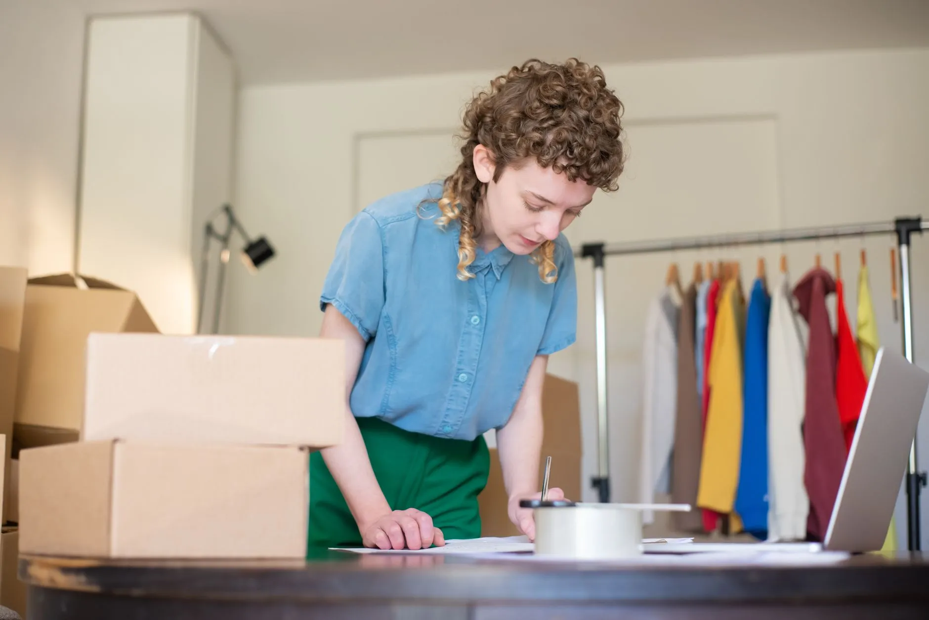 Emprendedora preparando pedidos de su tienda online junto al portátil